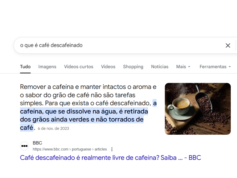 Imagem do Google exibindo um Featured Snippet para "o que é café descafeinado", com a resposta da BBC sobre a remoção da cafeína dos grãos verdes e uma foto de xícara de café.
